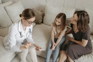 A doctor discussing results with a mother and young girl, representing the autism ADHD waiting list UK families experience